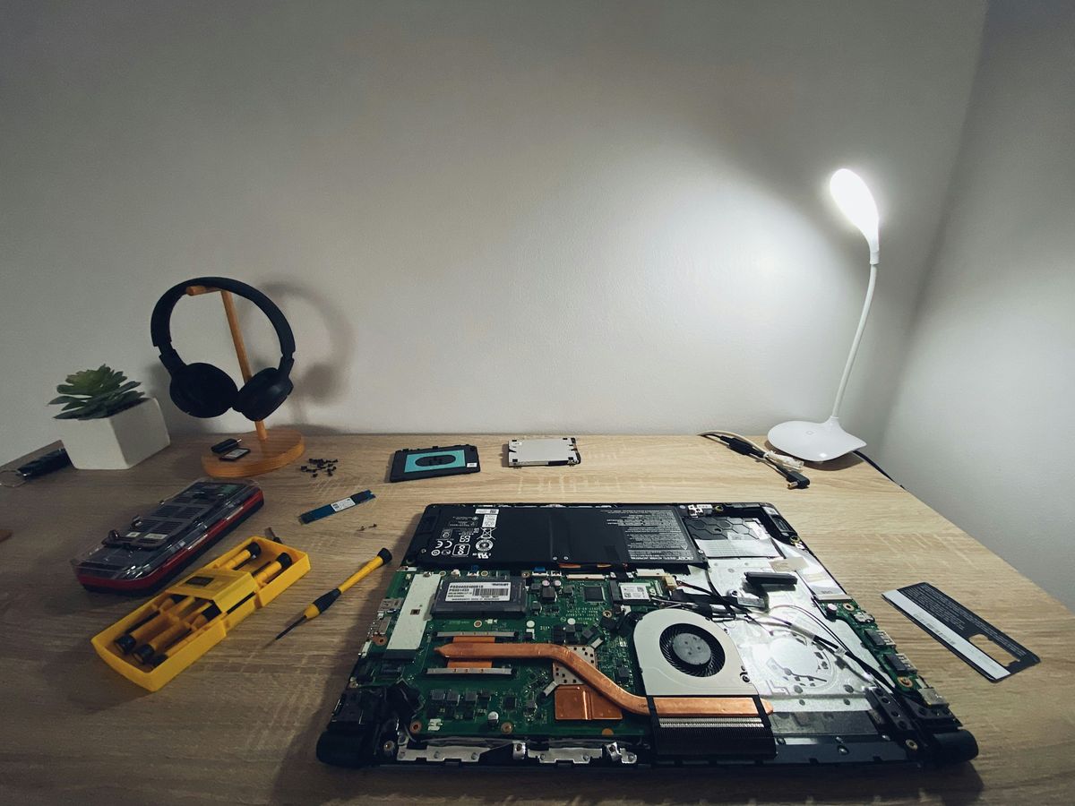 An opened laptop with tools on a desk