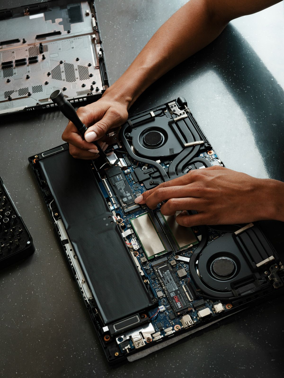 Hands working on the parts inside a laptop